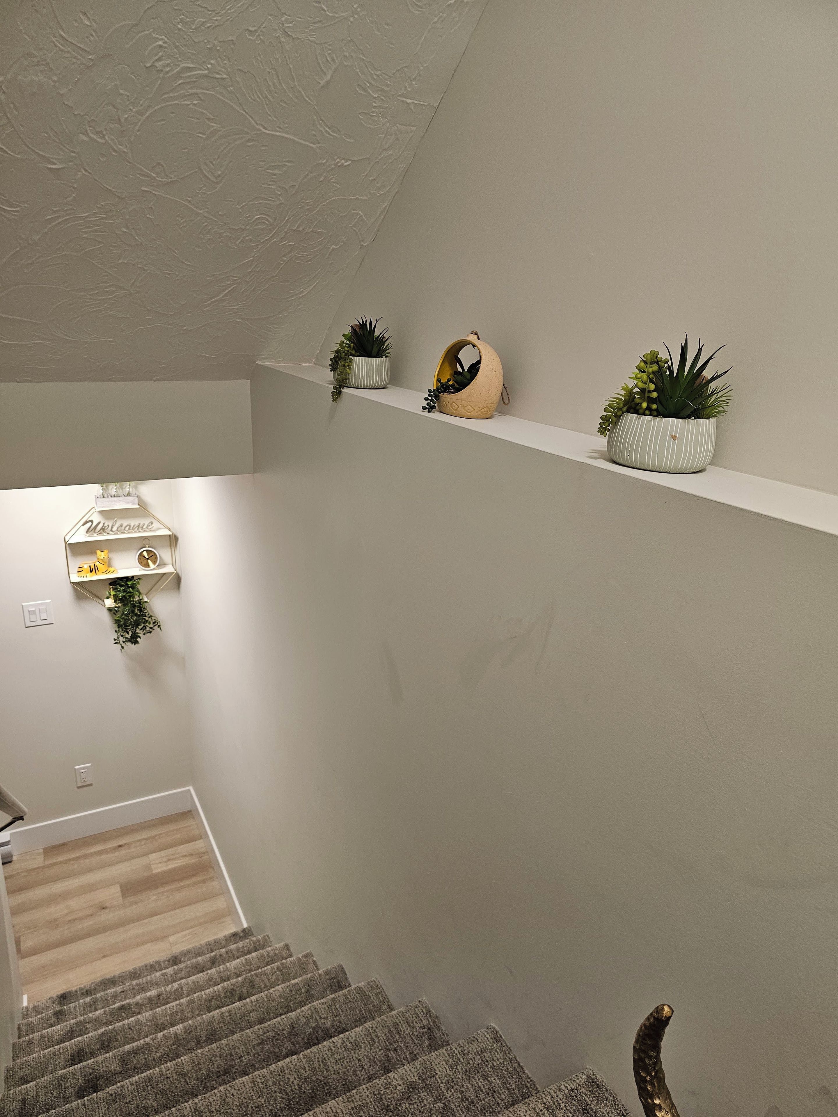 A staircase with a landing shelf holding potted plants and a decorative birdhouse.