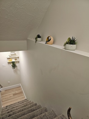 A staircase with a landing shelf holding potted plants and a decorative birdhouse. - Chester Luxury Suites - Brand New Moncton Getaway (Moncton)