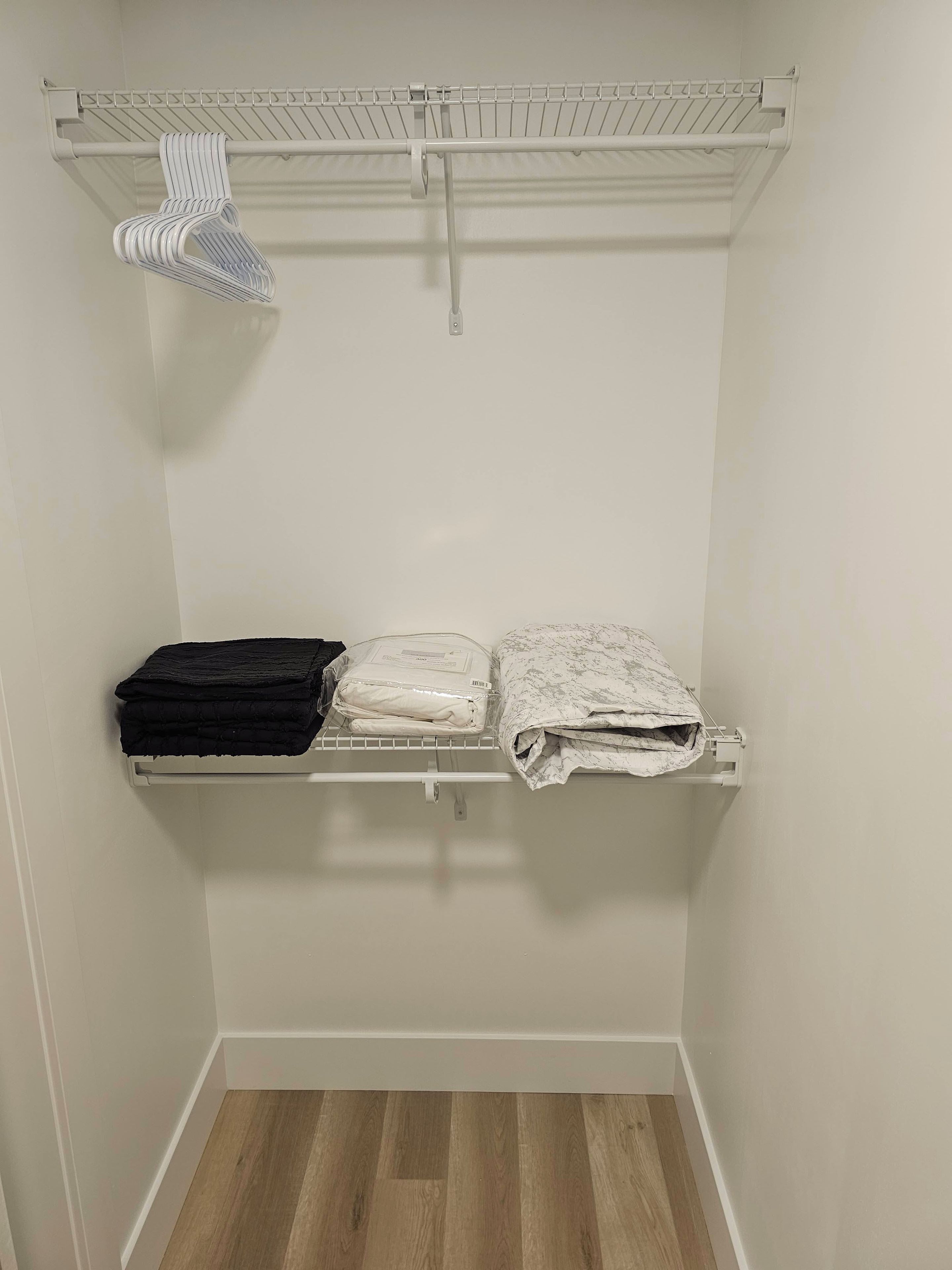 A closet with a hanging rack, shelves, and a folded clothes rack.