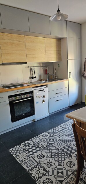 A modern kitchen with wooden cabinets, a built-in oven, and a patterned rug. - At the foot of the Alpilles, in the Arles-Avignon-Nîmes triangle (Saint-Étienne-du-Grès)