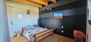 Une chambre à coucher avec un lit, une table de chevet, une lampe fixée au mur et un tableau.