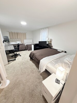 Ein Hotelzimmer mit Bett, Schreibtisch mit Computer, Stuhl, Fernseher und Nachttisch mit Lampe.