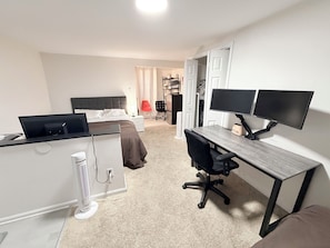 A bedroom with a bed, a desk with two monitors, a chair, and a radiator. - Spacious 5-bedroom 11 beds house in awesome Silver Spring with AC (Silver Spring)