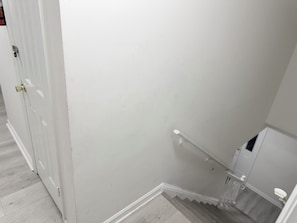 Eine Treppe mit Handlauf, eine Tür mit Messinggriff und eine weiße Wand.