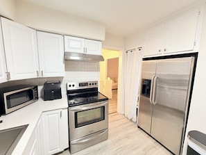 A modern kitchen with white cabinets, a stainless steel refrigerator, a built-in oven, and a microwave. - Spacious 5-bedroom 11 beds house in awesome Silver Spring with AC (Silver Spring)