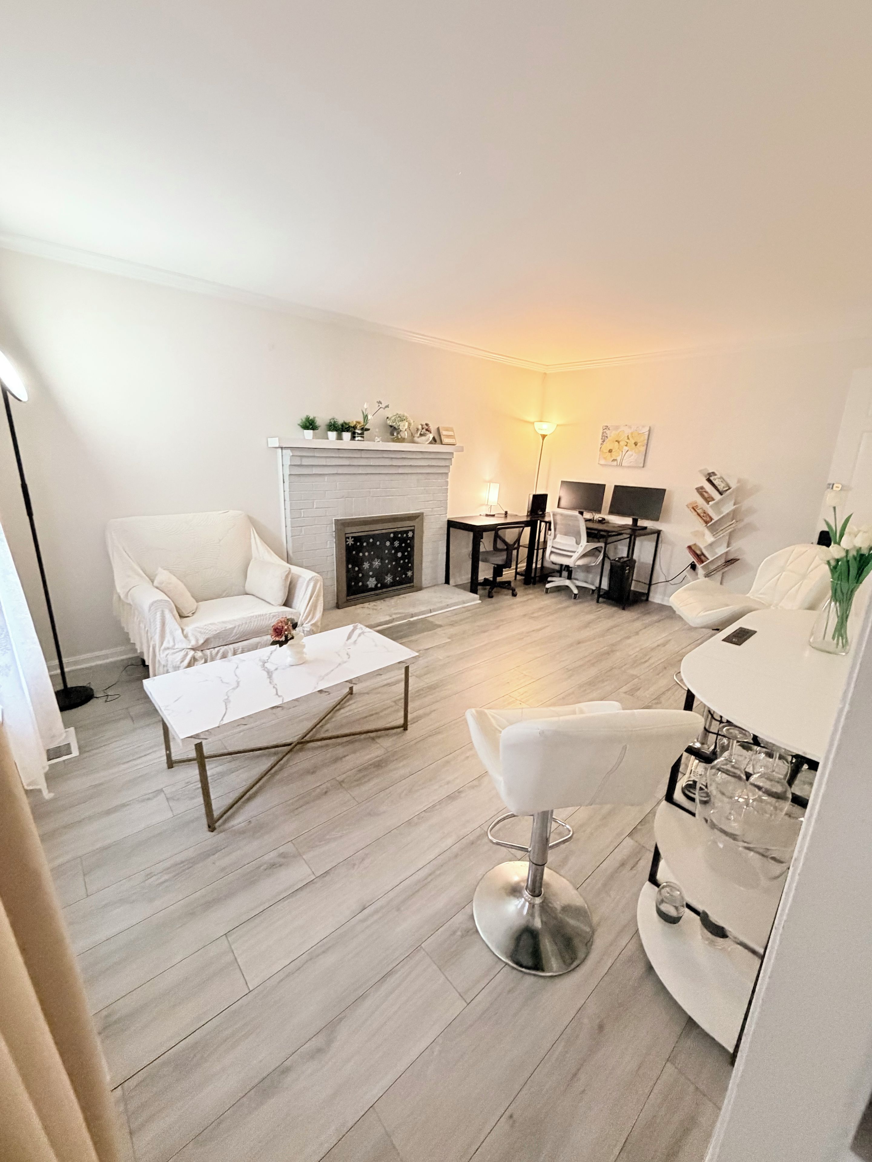 Een moderne woonkamer met een open haard, witte meubels en een eethoek met een glazen tafel.