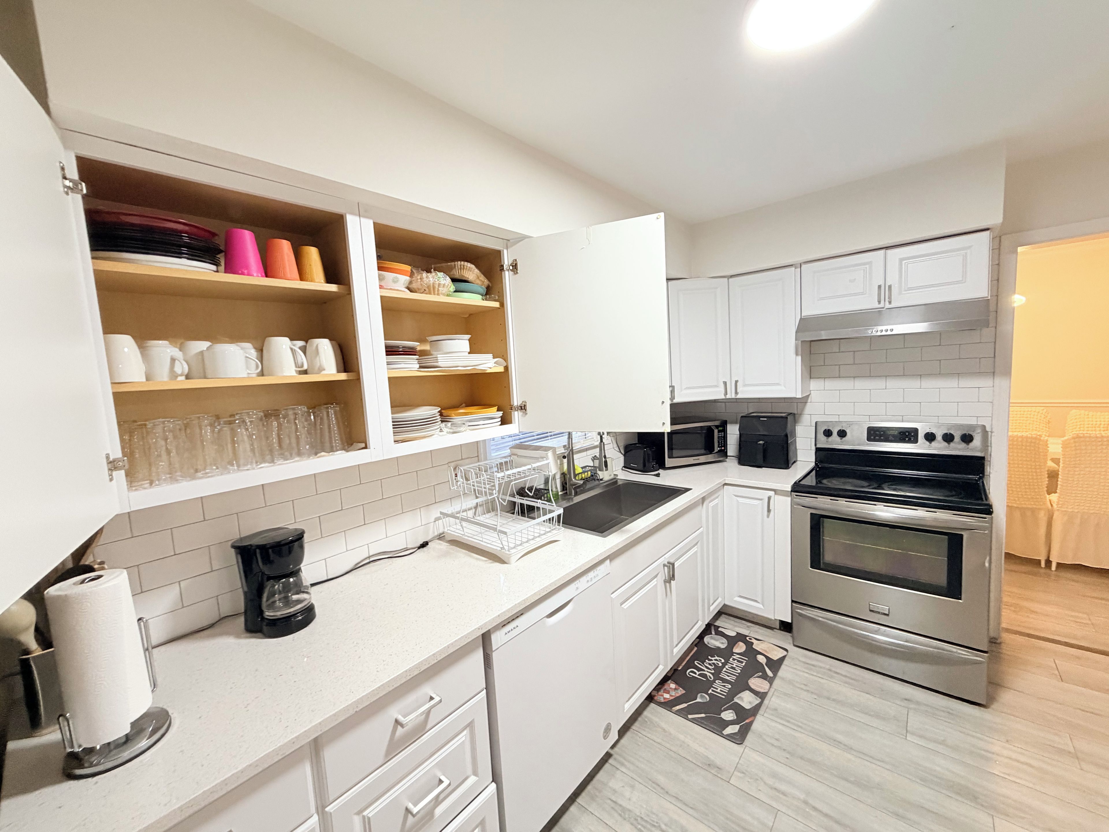 A modern kitchen with white cabinets, a stainless steel oven, and a dish drying rack.