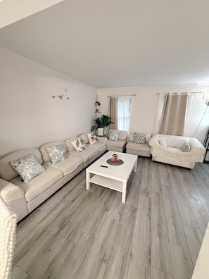 A living room with a sofa, armchair, and coffee table. - Spacious 5-bedroom 11 beds house in awesome Silver Spring with AC (Silver Spring)