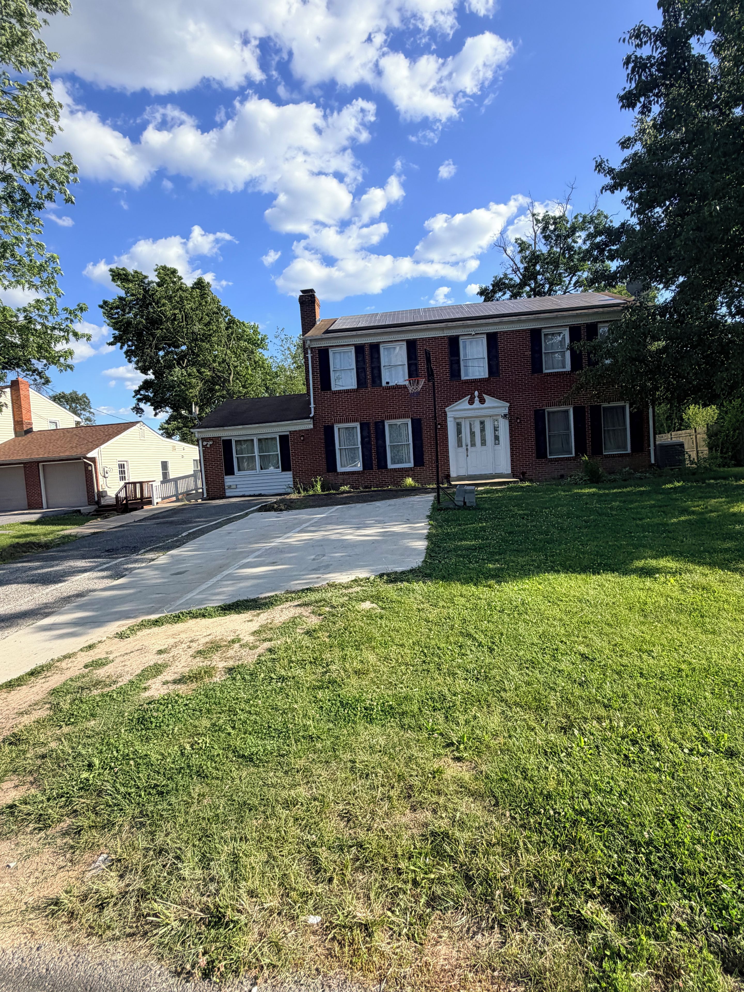 A two-story brick house with a front porch, a driveway, and a well-maintained lawn.