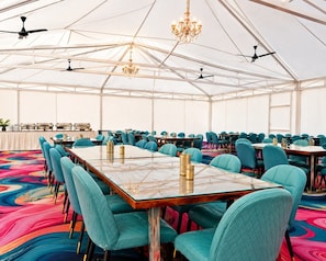 A large tented room with multiple tables and chairs, ceiling fans, and chandeliers. - The Desert Mafia Resort & Camp (Jaisalmer)