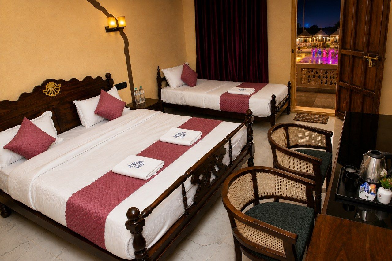 A hotel room with two beds, a desk, and a chair.