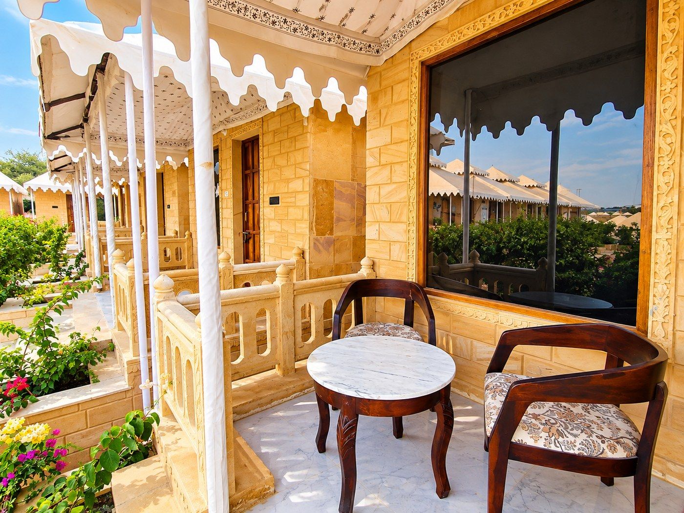 A traditional building with a balcony, a table, and chairs.