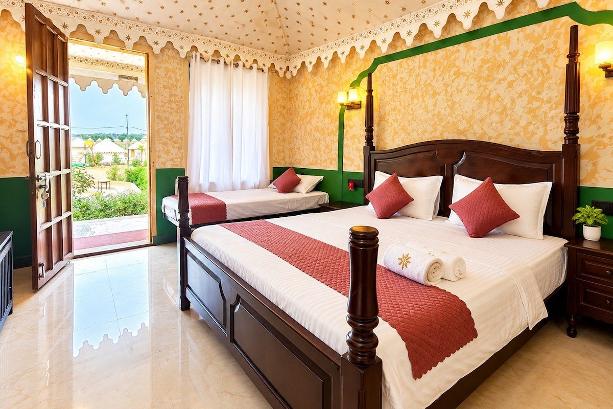 A hotel room with a four-poster bed, a second bed, a balcony, and a view of the surrounding area.