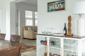 A dining area with a wooden table and chairs, a white cabinet with glass doors, and a 'gather' sign on the wall. - Brand new!! Water front home in serene Dania Beach. Located near airport. (Dania Beach)