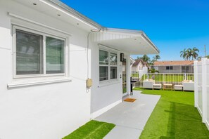 A white house with a covered porch, a small lawn, and a fence. - Brand new!! Water front home in serene Dania Beach. Located near airport. (Dania Beach)
