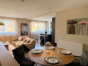 A dining area with a round table set for four, a sofa, and a kitchen in the background. - Vrbo Property (Vesoul)