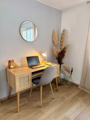 A wooden desk with a laptop, a lamp, and a vase with pampas grass. - Vrbo Property (Vesoul)