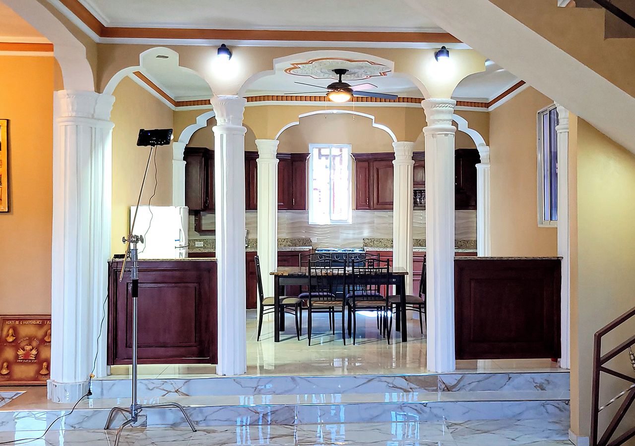Amplo interior com sala de jantar, cozinha e escada que leva a um andar superior.