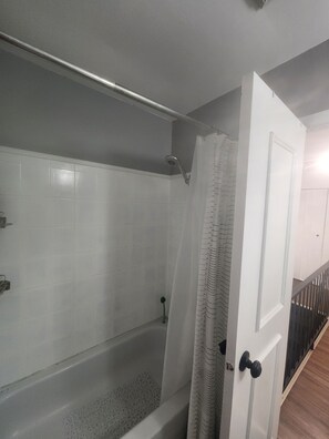 A bathroom with a bathtub, a shower, and a white door. - Charming & Cozy Guest House in Windsor (Windsor)