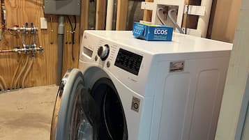 Een wasmachine met een voorlaadklep, een bedieningspaneel en een blauwe doos met de tekst 'ECOS' erop.