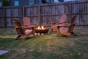 Two Adirondack chairs facing a fire pit with a wooden fence in the background. - The Fayetteville Trail House-1.5 miles from the U of A & next to Centennial Park (Fayetteville)