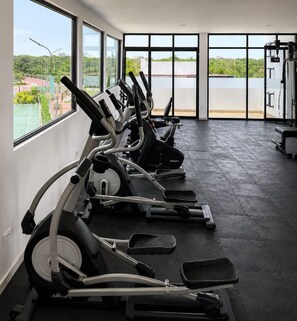 A gym with exercise equipment and large windows overlooking a body of water. - Casa Lamay | Clubhouse with a pool, internet, and a beach just a 15-minute drive away (Chuburná)