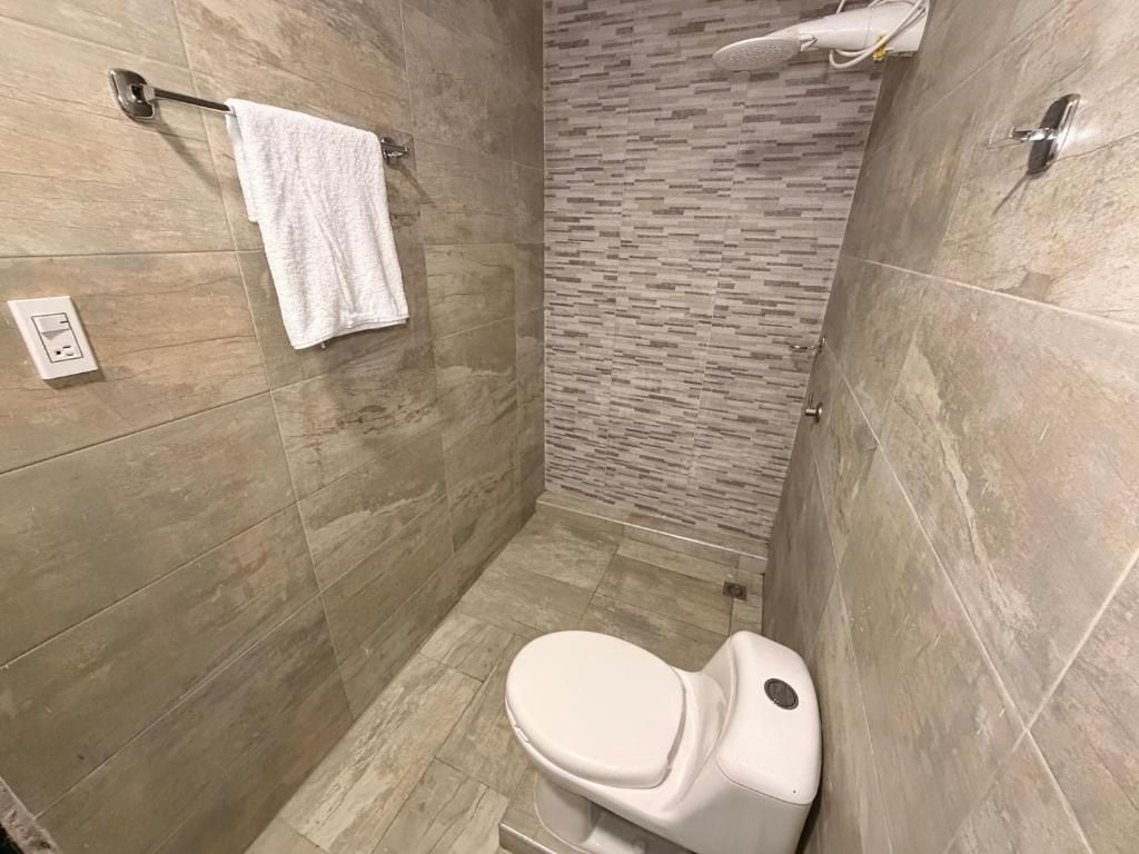 Un baño pequeño y moderno con inodoro, toallero y zona de ducha.