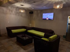 A living room with a sofa, a coffee table, and a television displaying 'BLACK COFFEE' on the wall.