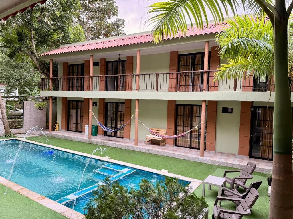 Un edificio de dos pisos con piscina, asientos exteriores y una hamaca.
