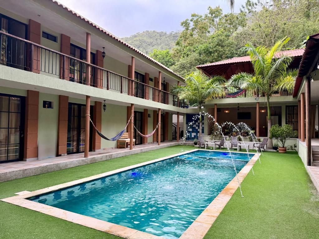 A hotel courtyard with a swimming pool, outdoor seating, and a view of a mountainous landscape.