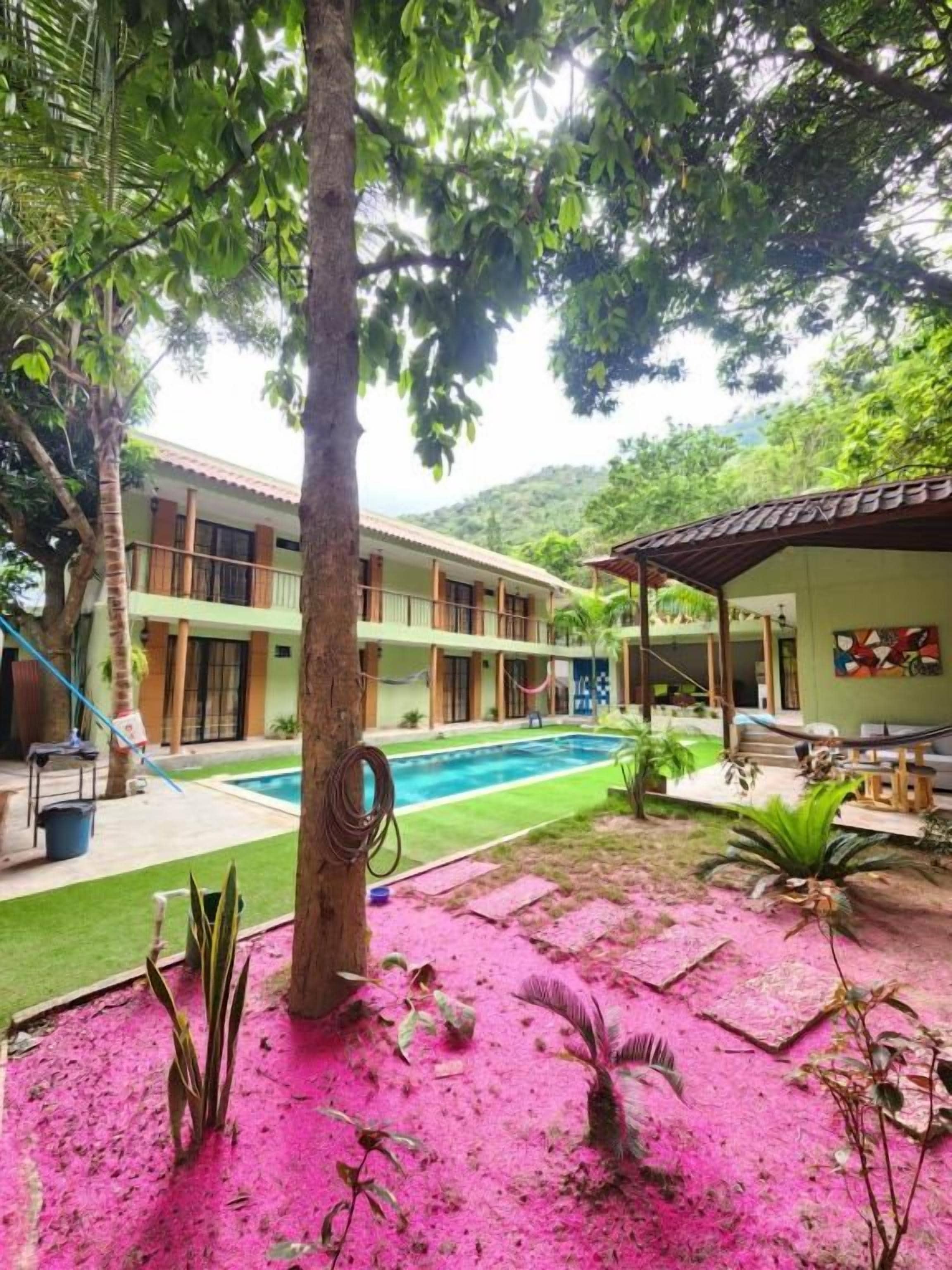 Un hotel con piscina, patio cubierto y vistas a un paisaje montañoso.