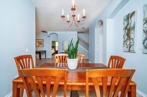 A dining area with a wooden table and chairs, a potted plant, and a chandelier. - LUXURY ORLANDO VACATION HOME PRIVATE HEATED POOL SLEEPS 11 NEAR DISNEY&UNIVERSAL (Davenport)