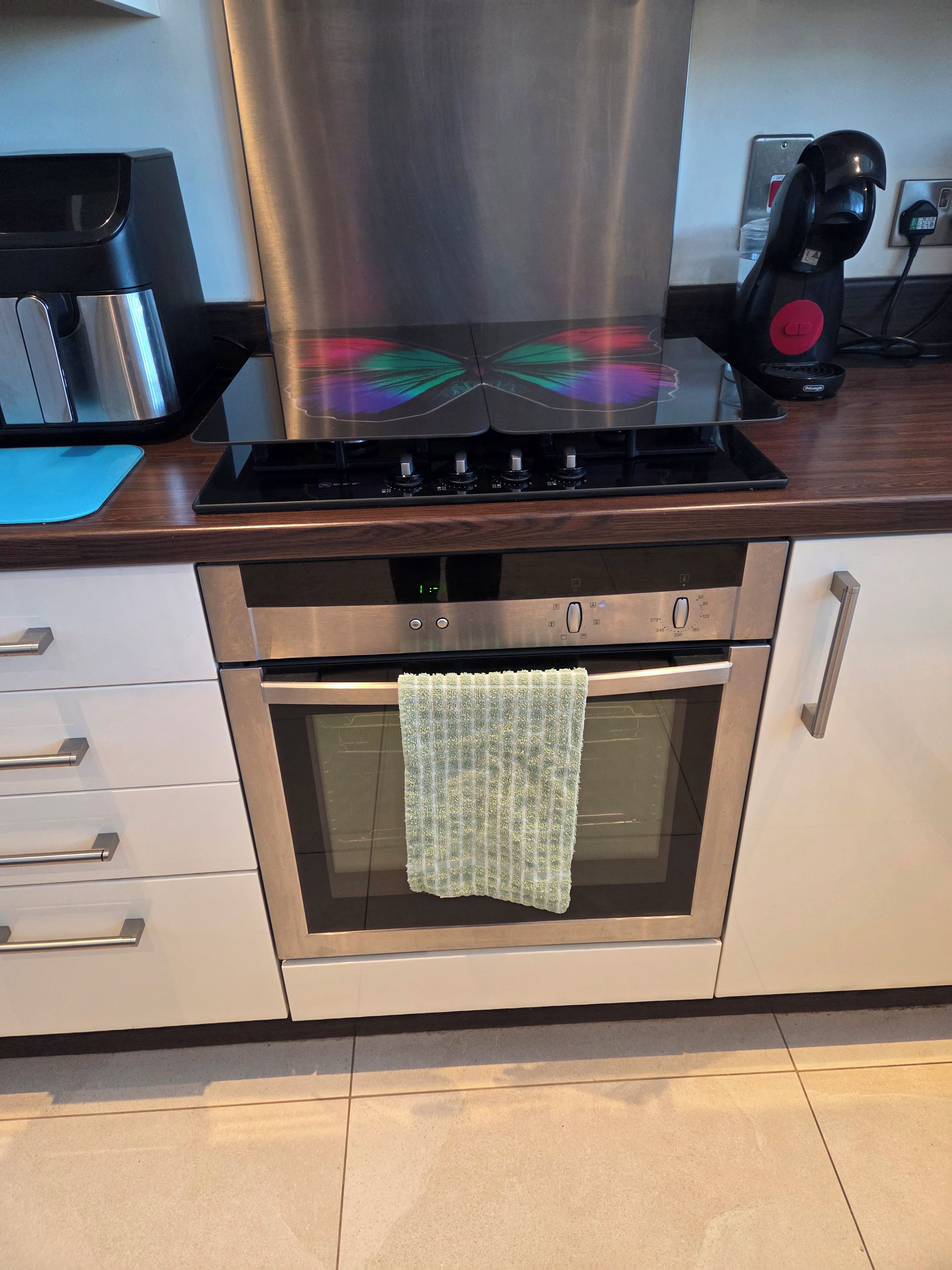 A kitchen with a stainless steel range hood, a built-in oven, and a coffee maker on the counter.