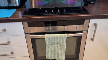 A kitchen with a stainless steel range hood, a built-in oven, and a coffee maker on the counter.