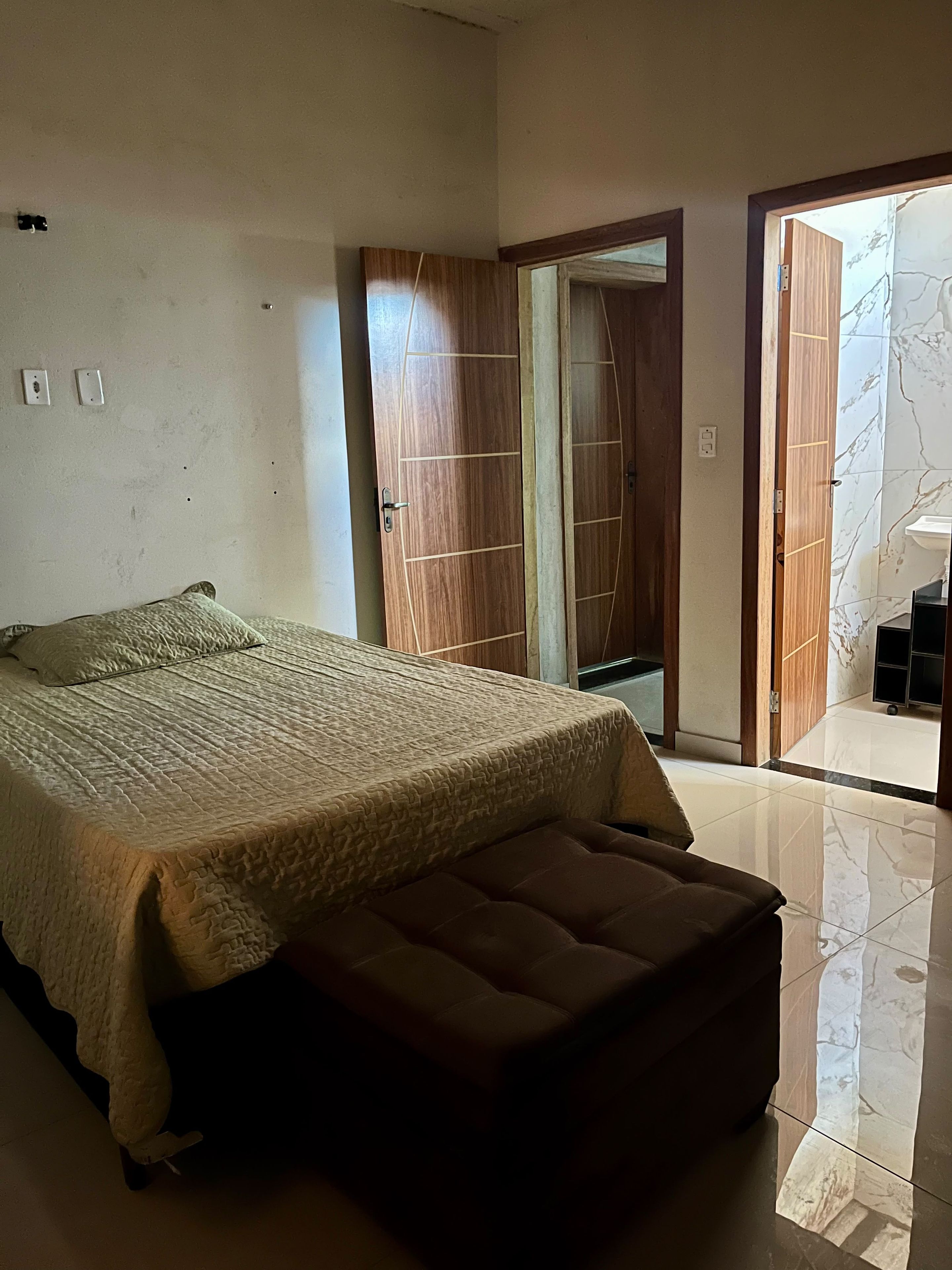 Ein Schlafzimmer mit einem Bett, einer Bank, einem Kleiderschrank und einem Badezimmer mit Marmorboden.