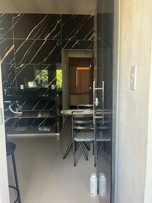 Eine moderne Küche mit schwarzem Marmorfliesenspiegel, einem Essbereich mit rundem Tisch und Stühlen sowie Blick in einen Raum mit einer Holztür.