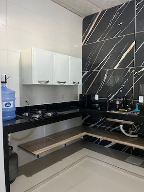 Una cocina con armarios blancos, un salpicadero de mármol negro y un dispensador de agua azul.