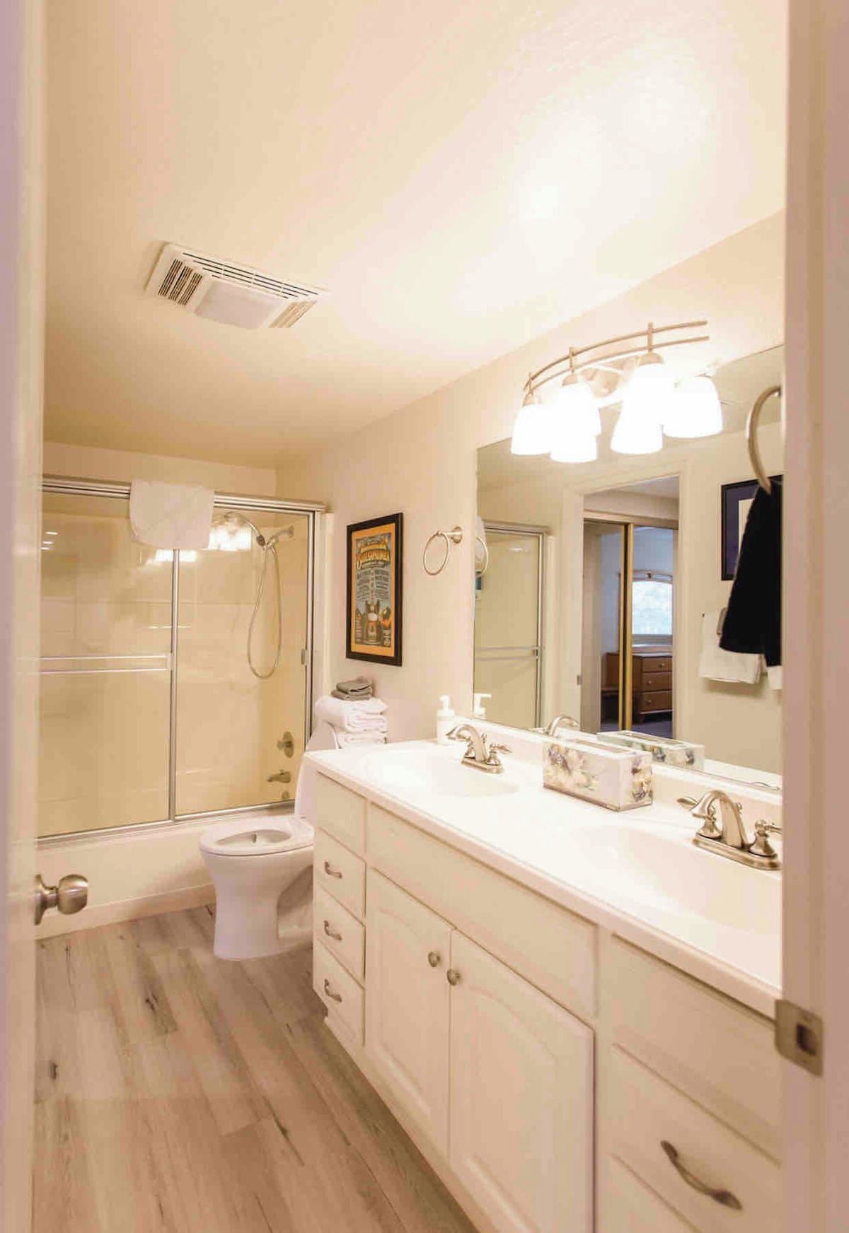 A bathroom with a shower, toilet, vanity with a mirror, and a sink.