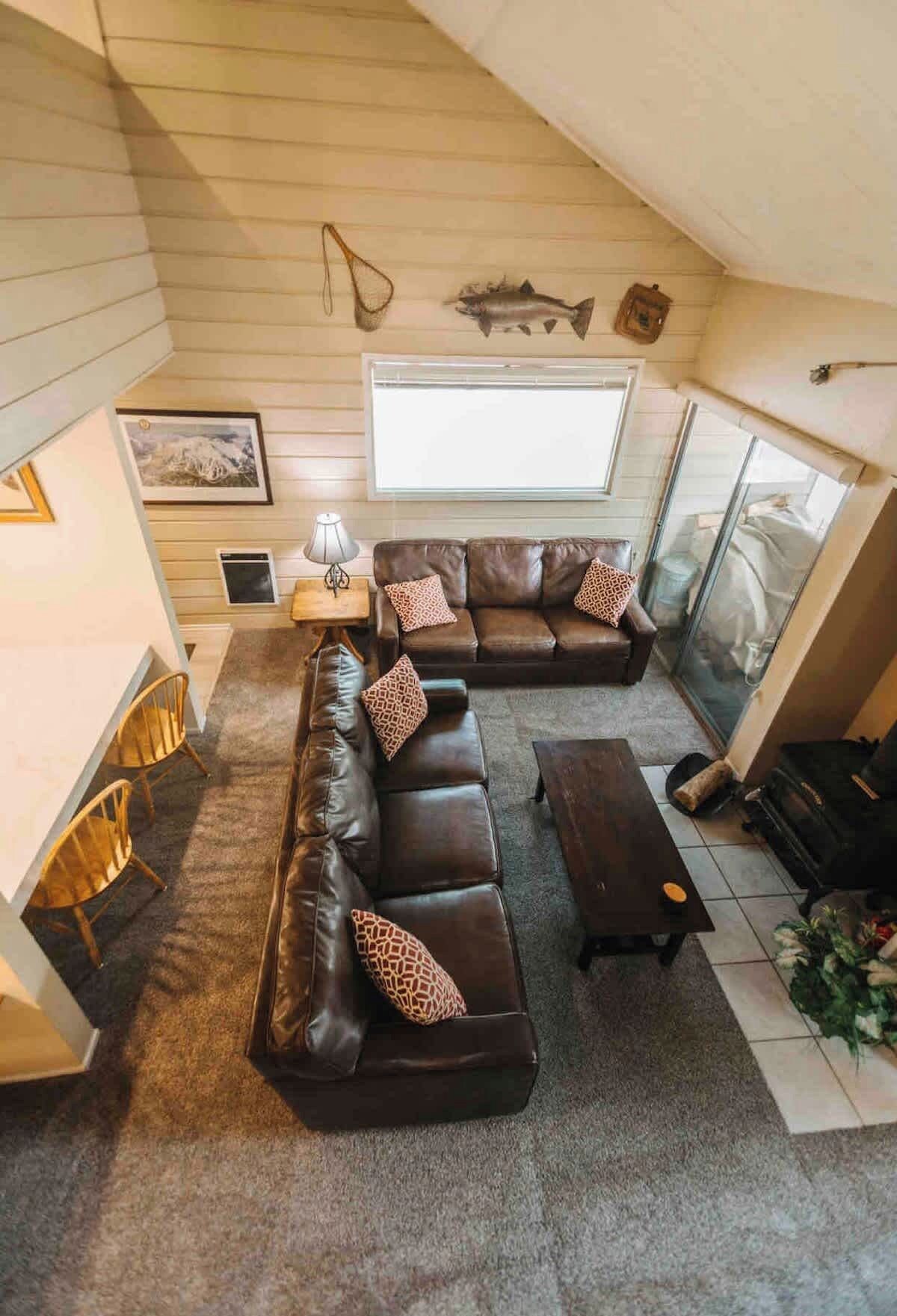 Een gezellige woonkamer met een hoekbank, een bijzettafeltje en een open haard.