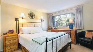 A bedroom with a bed, bedside tables, a dresser, a window with curtains, and a chair.
