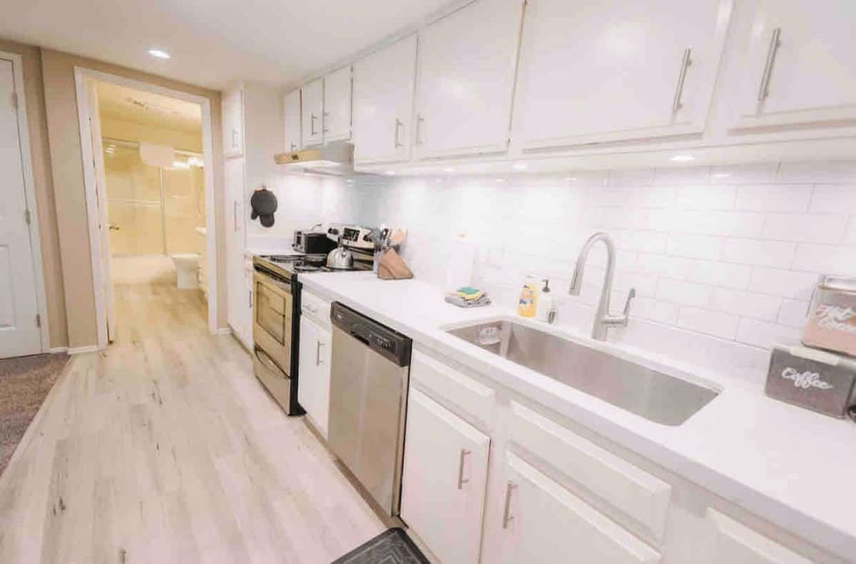 A modern kitchen with white cabinets, a dishwasher, and a sink.