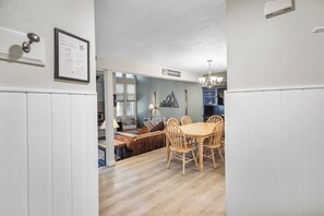 A dining area with a wooden table and chairs, a sofa, and a chandelier. - Mammoth Spacious Townhouse 2 Bd w/self check in (Mammoth Lakes)
