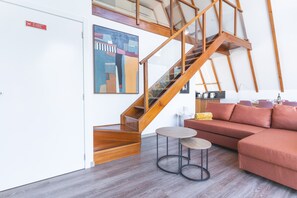 Ein modernes Interieur mit einer Holztreppe, einem Sofa, einem kleinen Tisch und einem Bild an der Wand.