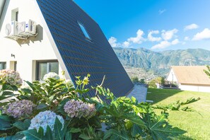 A modern house with a sloped roof, solar panels, and a garden with hydrangea flowers. - Star Lodge by Atlantic Holiday (São Vicente)