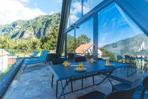 Eine Terrasse mit Tisch für zwei Personen mit Blick auf eine gebirgige Landschaft.