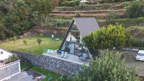 A modern house with a glass facade, a stone retaining wall, and a grassy yard. - Star Lodge by Atlantic Holiday (São Vicente)