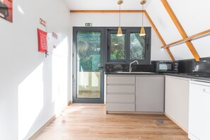 A kitchen with a black door, a sink, a microwave, and a wooden ceiling. - Star Lodge by Atlantic Holiday (São Vicente)
