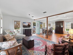 A spacious living room with a large flat-screen TV, a dining area with wooden chairs, and a view of the outdoors through large windows. - Historic Two Bedroom Apartment Overlooking Olde Towne Daphne (Daphne)