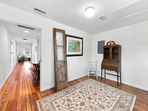 A hallway with hardwood flooring, a large rug, a wooden cabinet, and a door leading to another room. - Historic Two Bedroom Apartment Overlooking Olde Towne Daphne (Daphne)