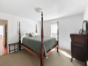 A four-poster bed with a green bedspread, a wooden nightstand, and a dresser with a mirror and picture frame. - Historic Two Bedroom Apartment Overlooking Olde Towne Daphne (Daphne)